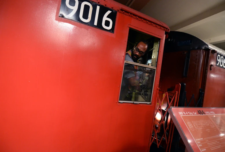 a man looks out the window from inside a red train
