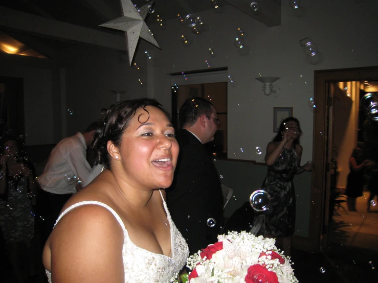 the woman is happily posing for the camera, she's being surrounded by bubbles