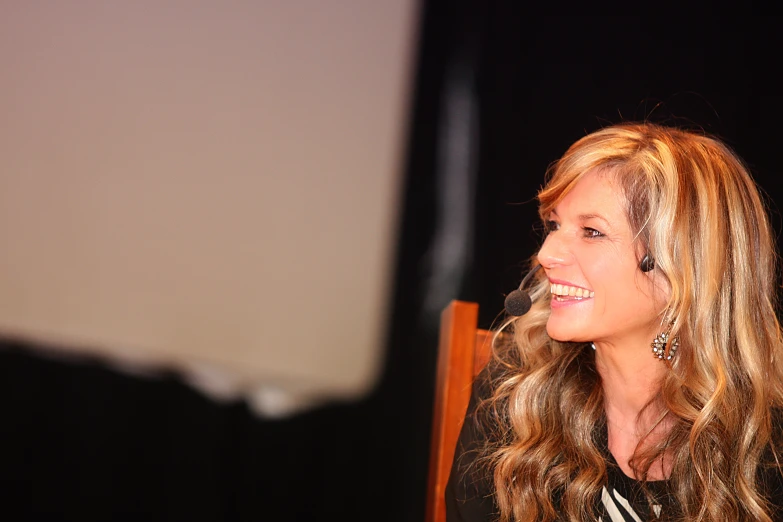 a beautiful young blond woman sitting down with a microphone