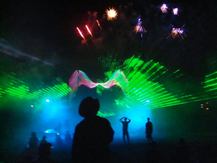 people standing at a concert under brightly lit beams