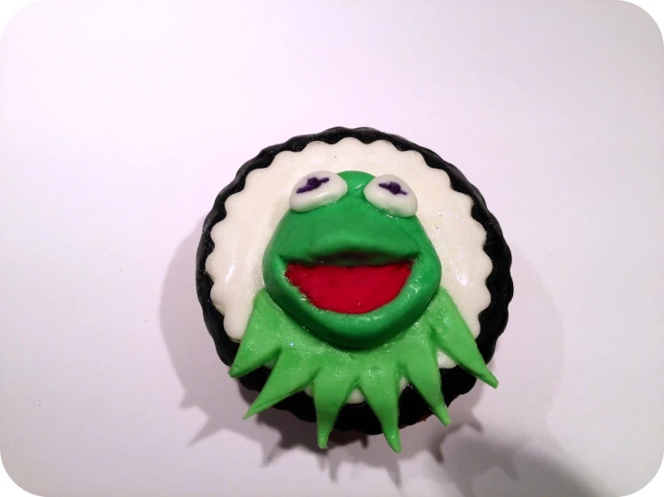 there is a cupcake with gummy monster on top