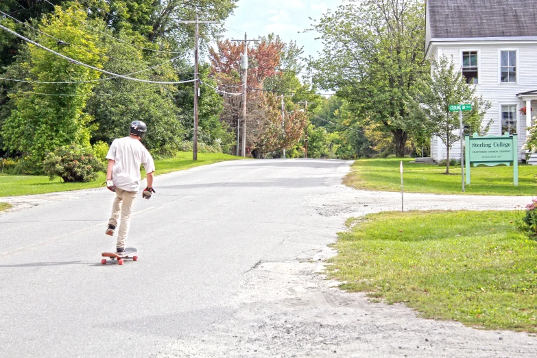 a man skateboarding down a street with trees in the background