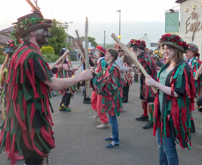 people dressed in colorful outfits holding stick sticks