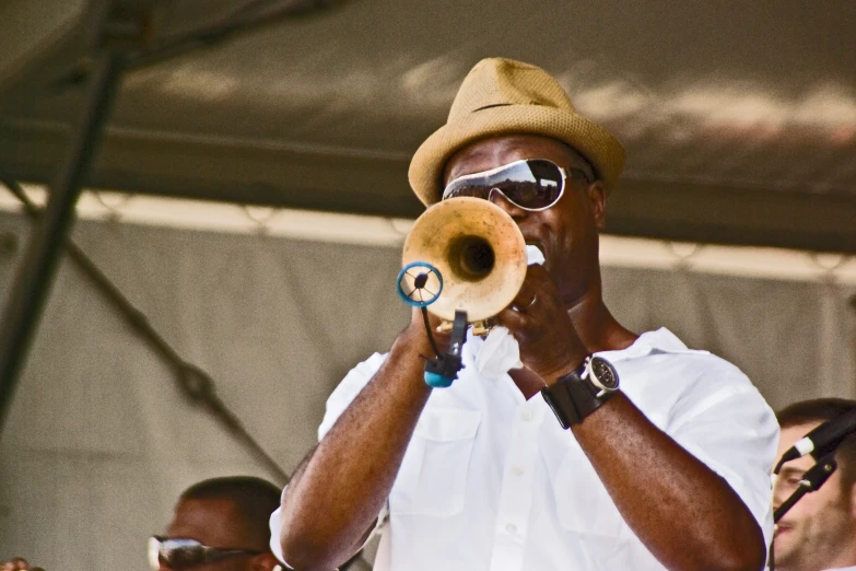 man wearing a hat and glasses holding up a trumpet