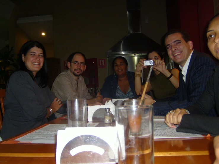 a group of people sitting around a table with glasses of water and chopsticks