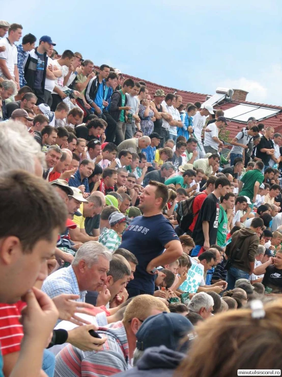 a crowd of people sitting in a stands in front of a fence