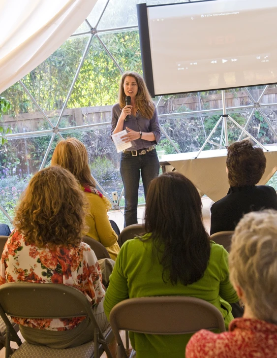 woman on stage speaking at outdoor event with group