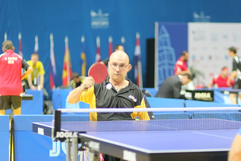 a man with a bald head plays ping pong
