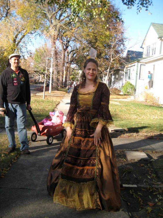 a man and woman walking down a sidewalk wearing renaissance style dresses