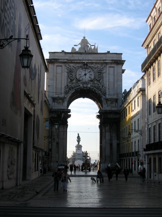 people walking under a large, ornate archway