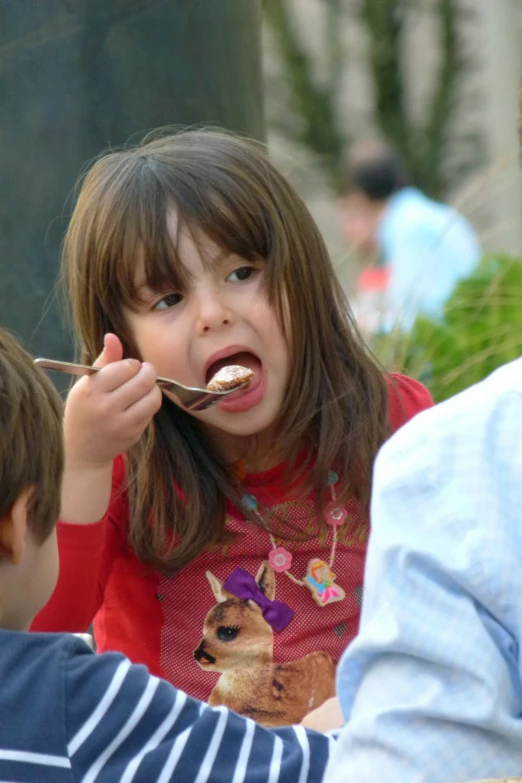 a little girl with a spoon eating food