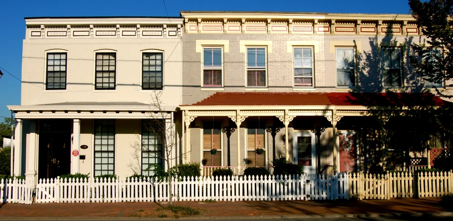 there is a two story house that has a white picket fence