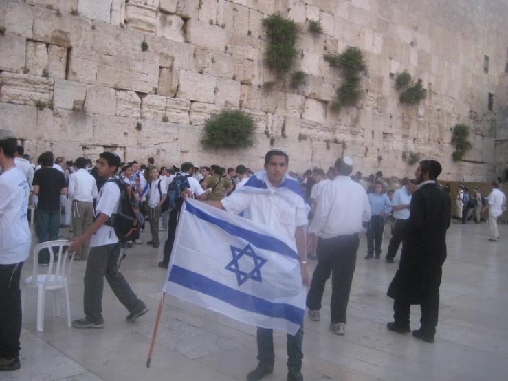 the man is holding an israeli flag in front of a large wall