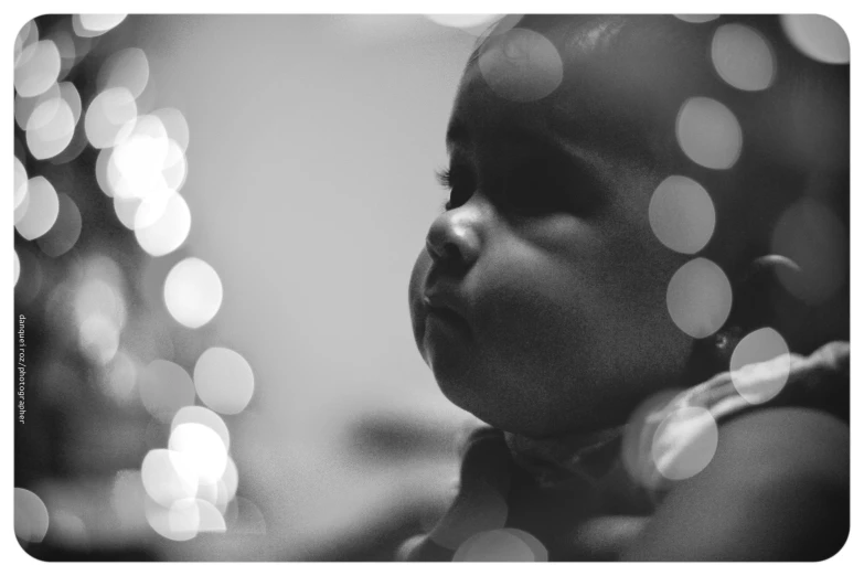 a black and white pograph of a baby looking at the camera