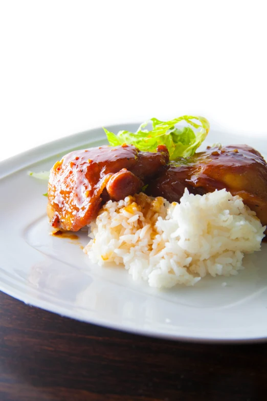 a white plate topped with rice and meat covered in sauce