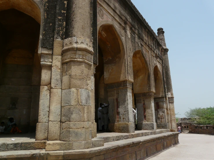 a couple of people standing near old columns