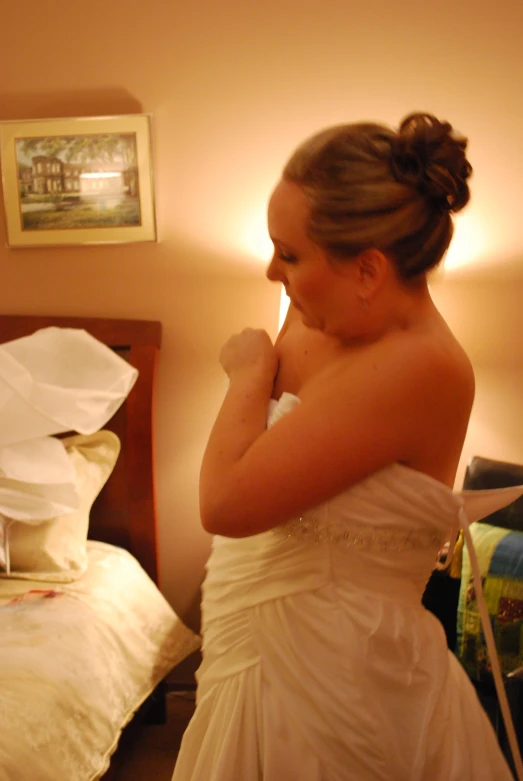 a woman in a wedding dress standing in a bedroom