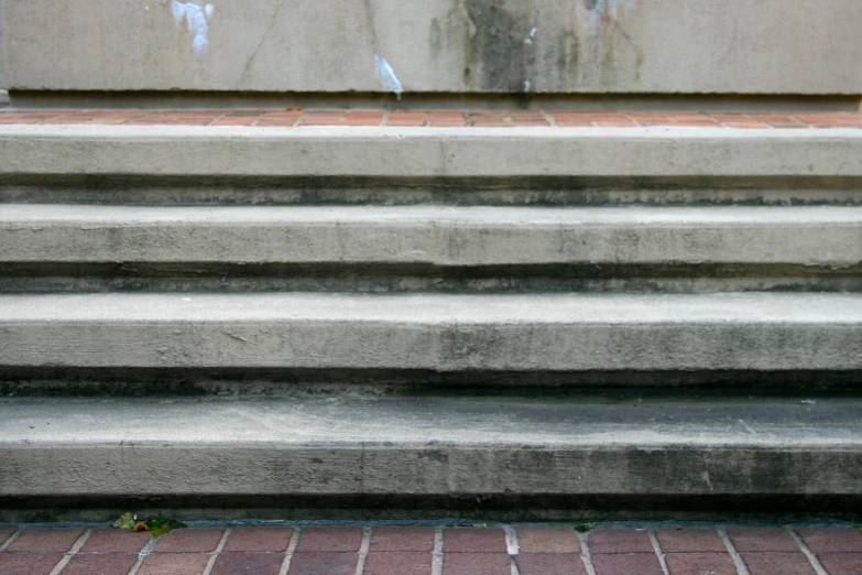 three concrete steps on red bricks on a street