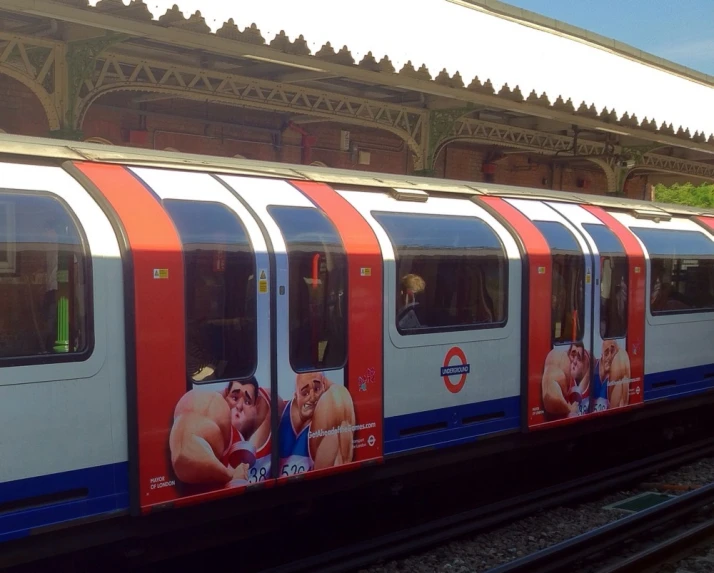 the train is traveling past a platform with advertising on it