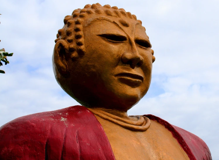 a large statue is posed under the cloudy sky