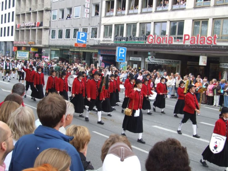 a group of people walking across a street in front of a building