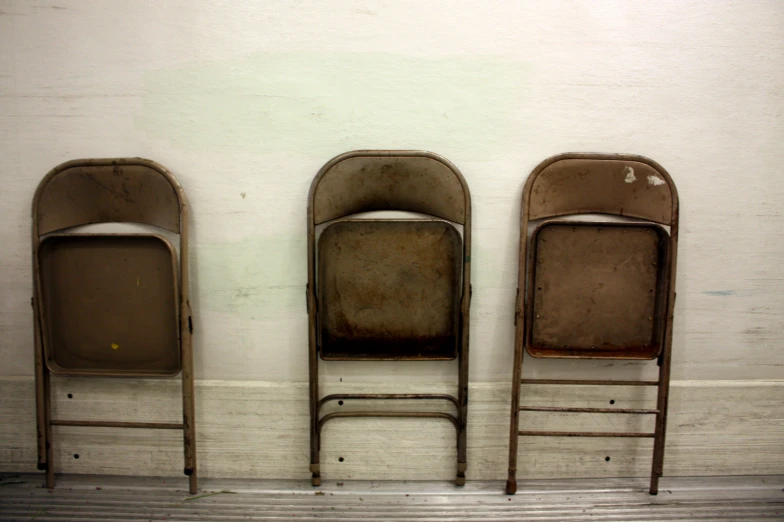 old folding chairs stand in front of a white wall