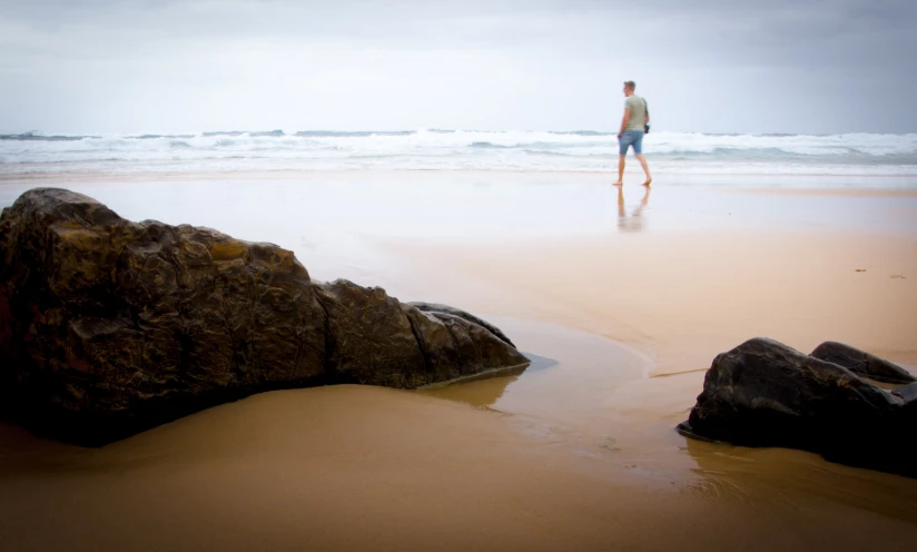 a man is walking on the beach with his surf board