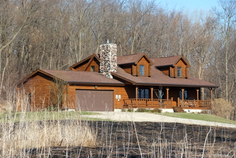 a log home with three windows and a wraparound patio