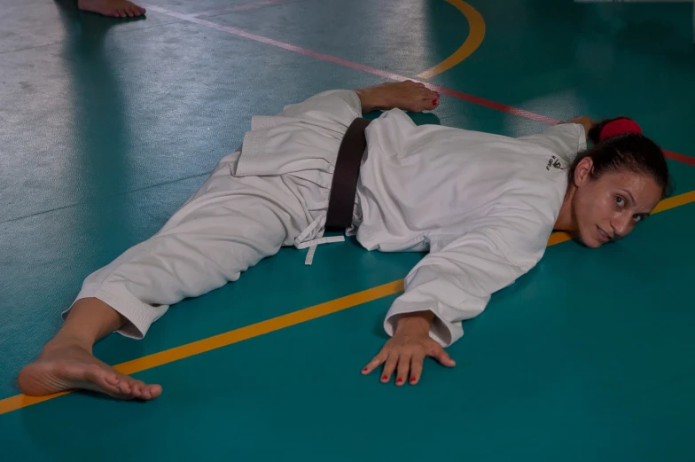 a woman is laying on the ground wearing a karate suit