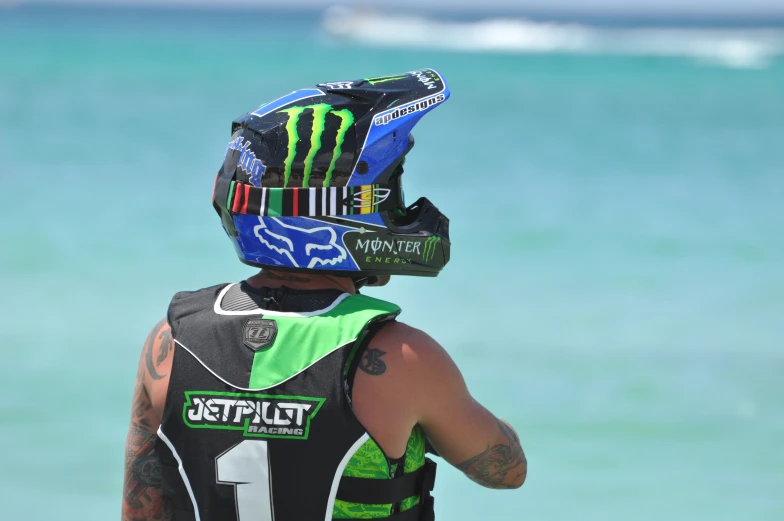 a motorcycle rider with a helmet on looking out to the water