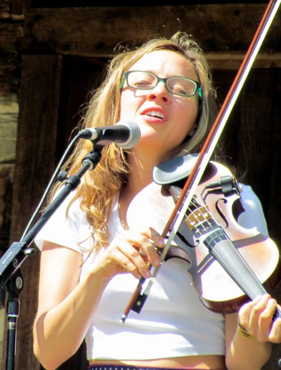 a girl with glasses playing violin on a stage