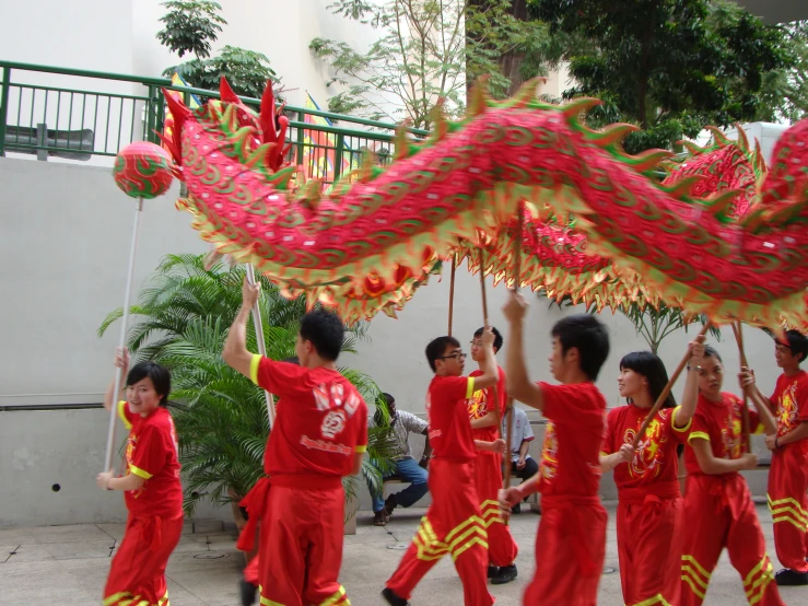 a group of people standing around each other holding a red dragon puppet