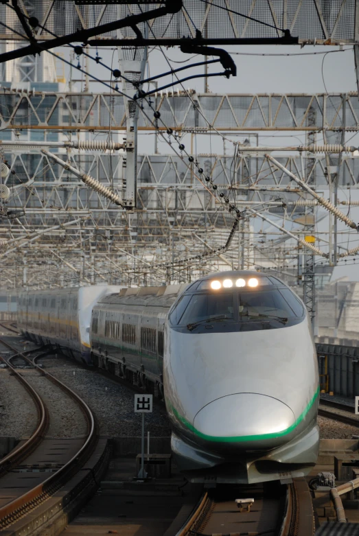 a white train going down tracks surrounded by steel structures