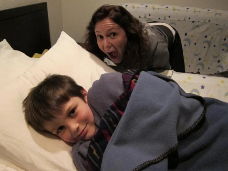a small child laying in bed with a woman