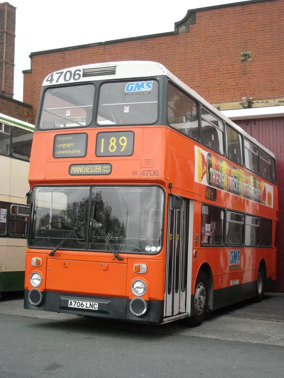 an orange double decker bus parked outside of a building