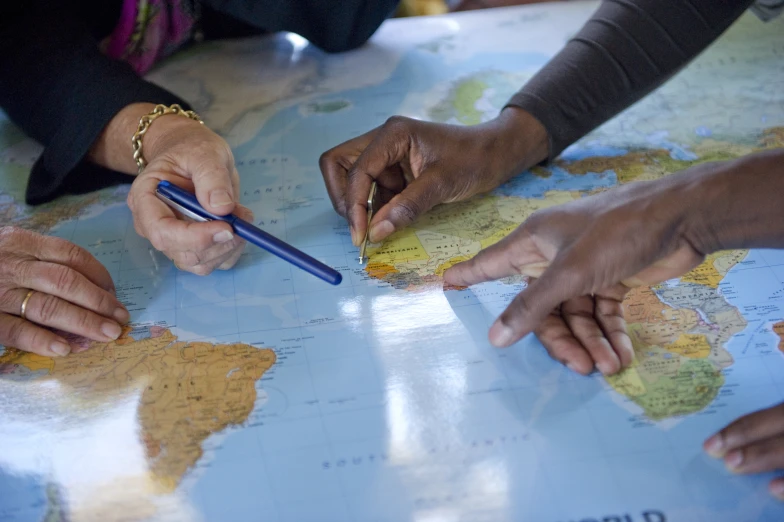 a group of people pointing to a map on the table