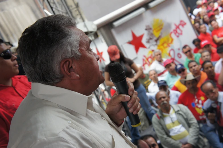 a man with glasses speaking into microphone in front of an audience