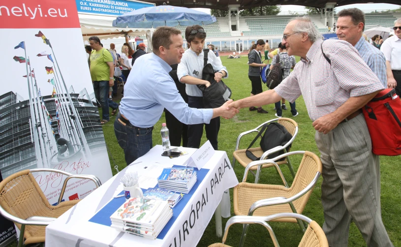 men shaking hands at an event on the grass