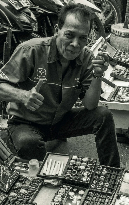 a man crouching on a table surrounded by various assorted items