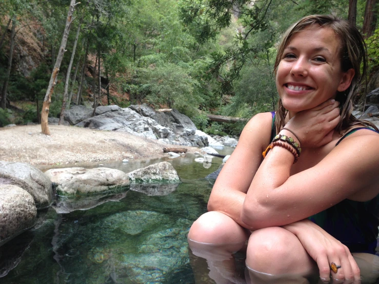 a girl smiles while posing for a po in a body of water