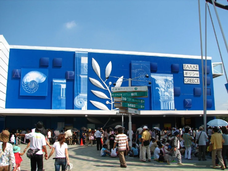 a crowd of people stand in front of a blue building