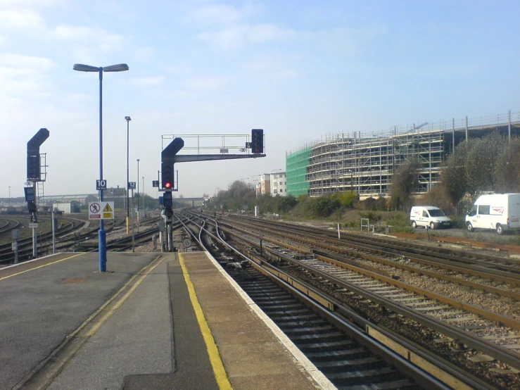 a train platform with an overhead rail bridge in the background