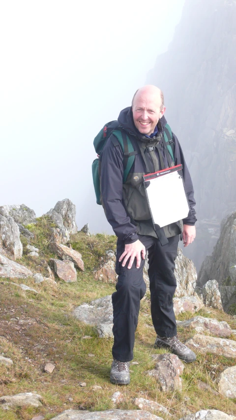 a man with a backpack on a mountain side standing in the mountains