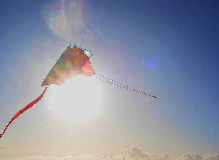 a sun shines through the sky over a kite