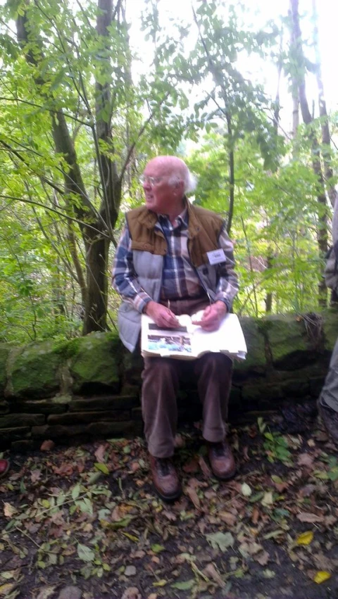 two older men are sitting on a rock and looking at soing