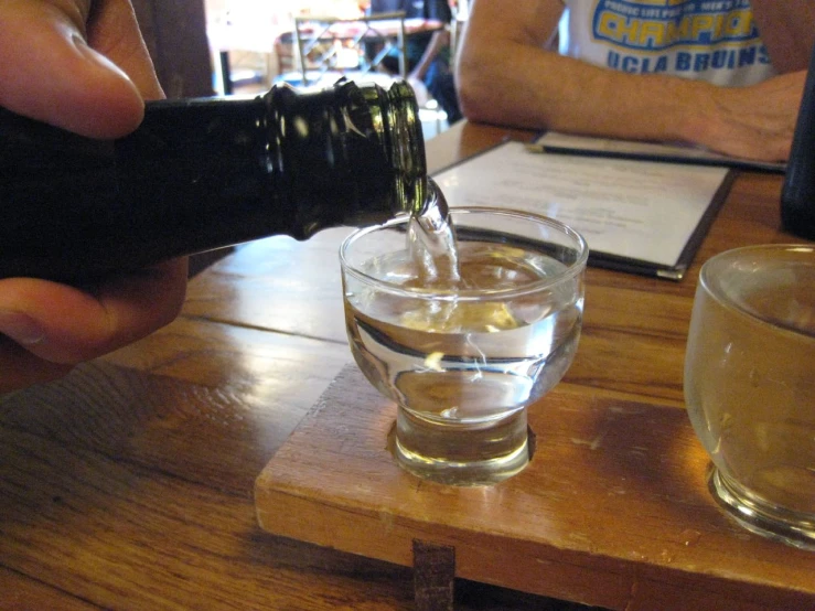 someone pouring their glasses filled with water from a bottle