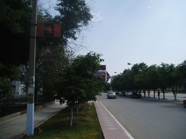 an empty street with green grass and trees next to it