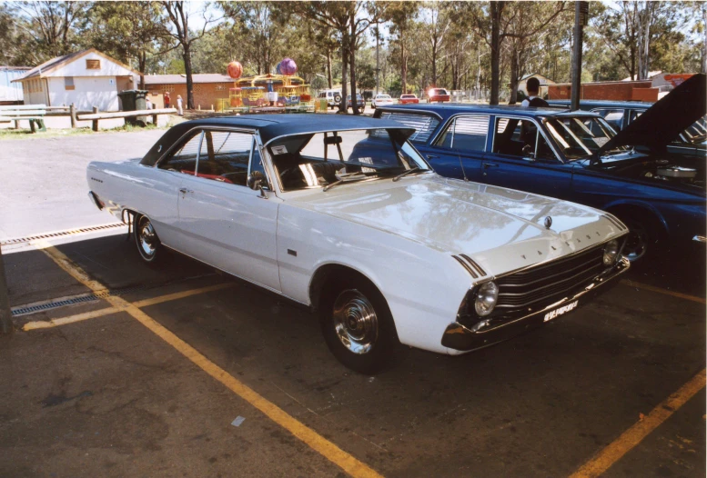 several classic cars parked side by side in a parking lot