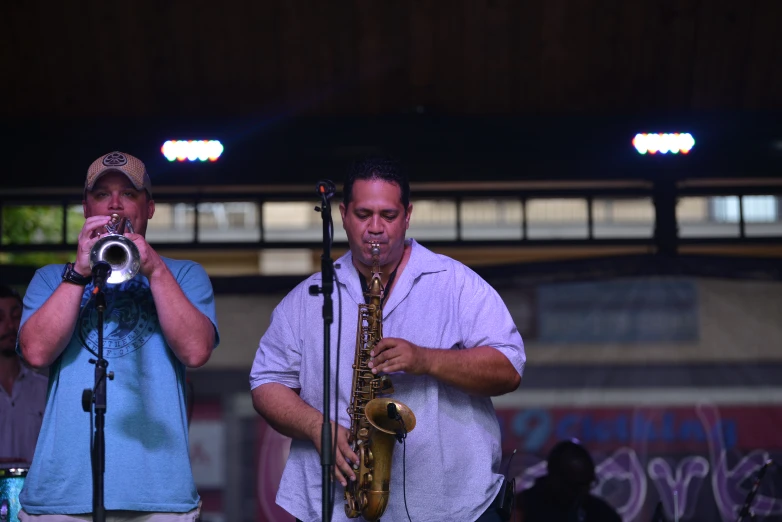 two men standing with their saxophones playing on stage