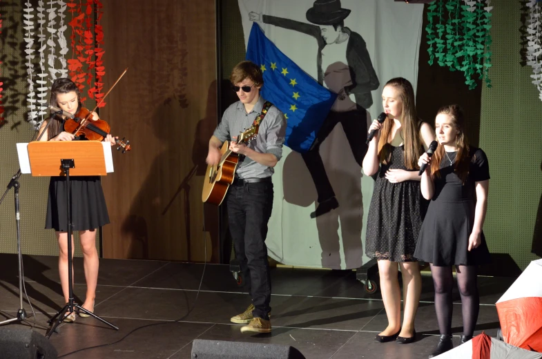 a band playing on stage with some people standing by